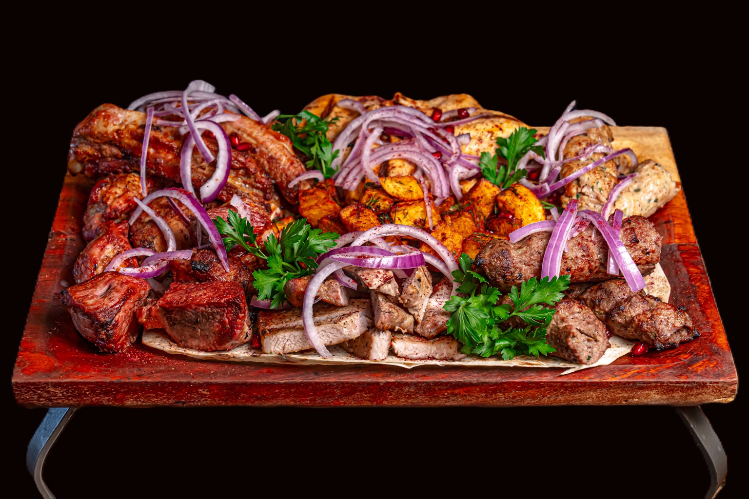 Guda meat plate with grilled meats, potatoes, onion and herbs