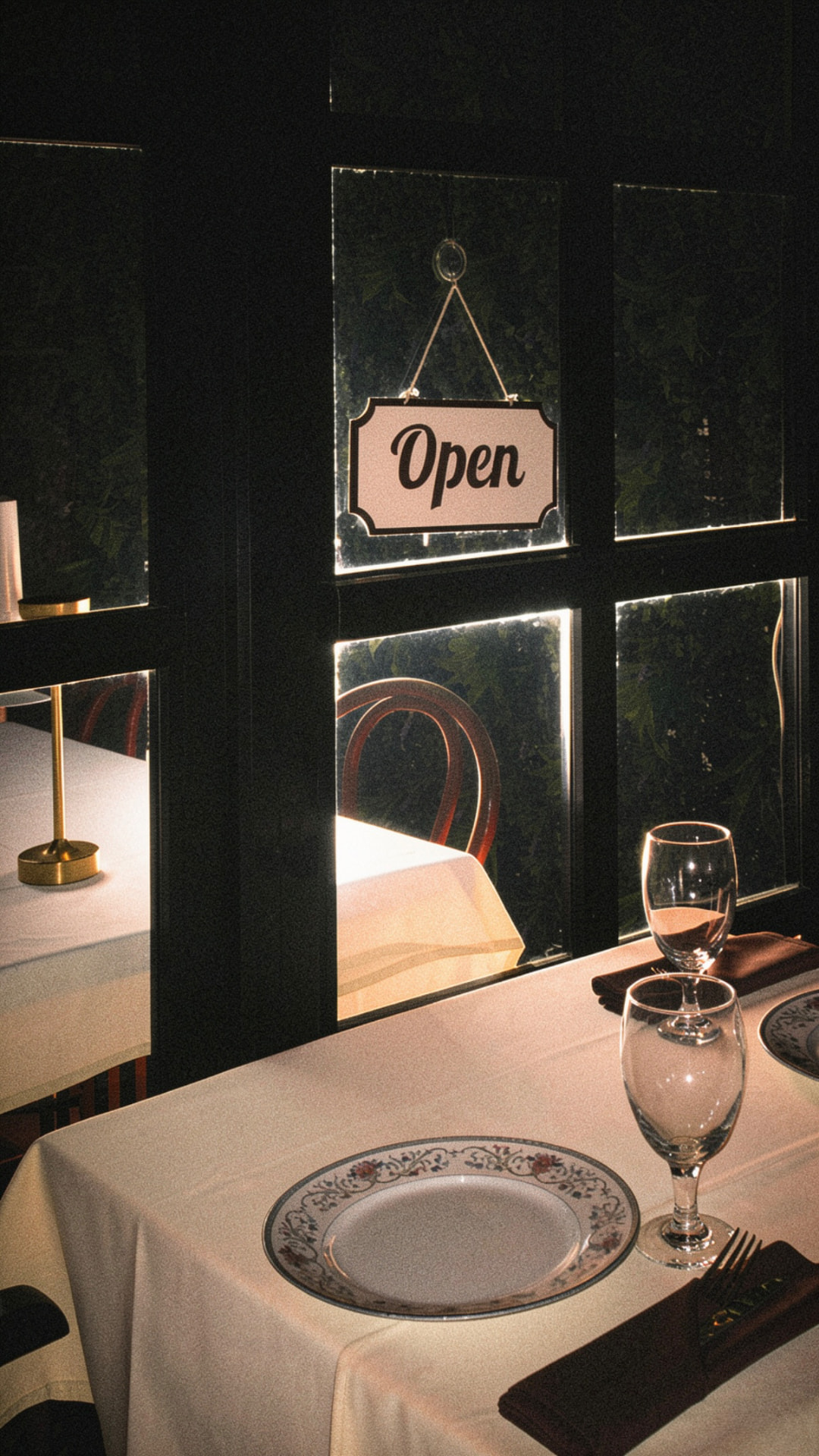 Evening light through the windows of Guda, with the Open sign hanging in the glass